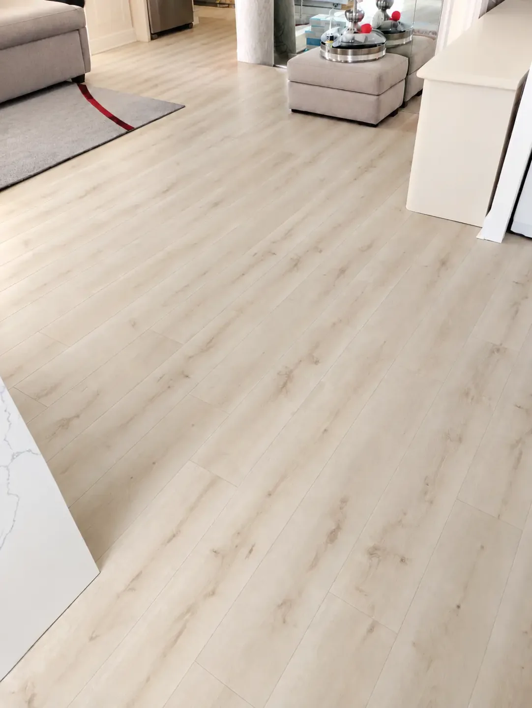 Light wood-look plank flooring across a furnished living room with gray rug and upholstered seating