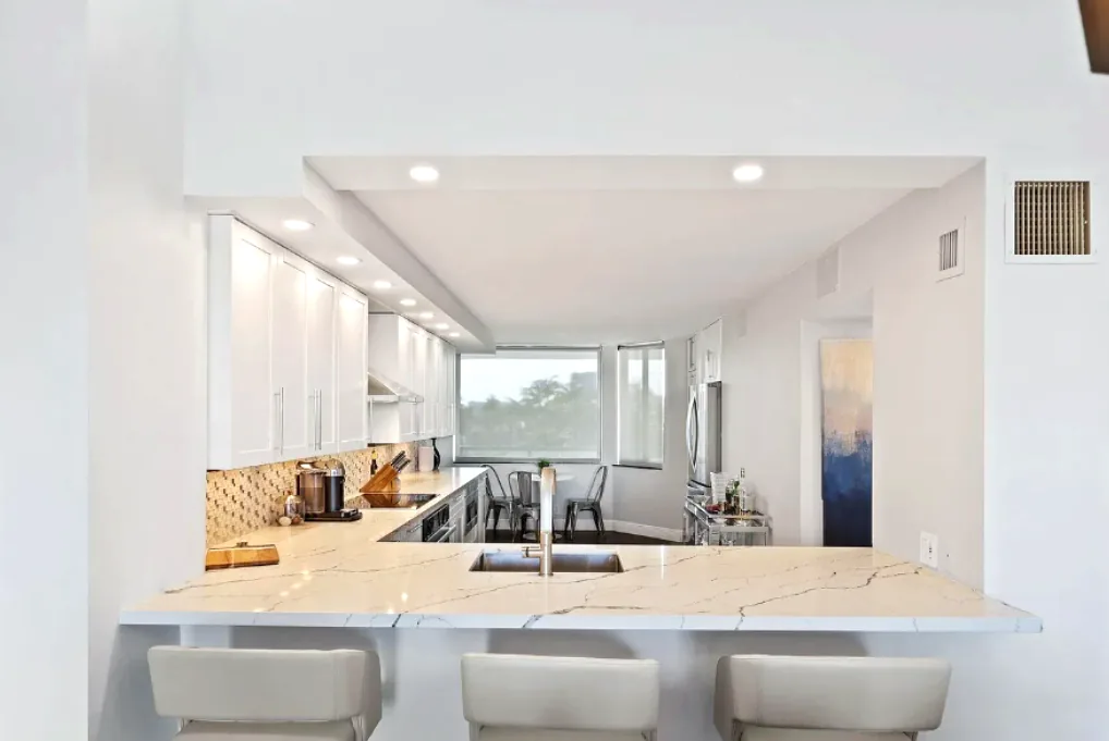 Kitchen pass-through with a marble-look breakfast bar counter and bar seating open to the living area