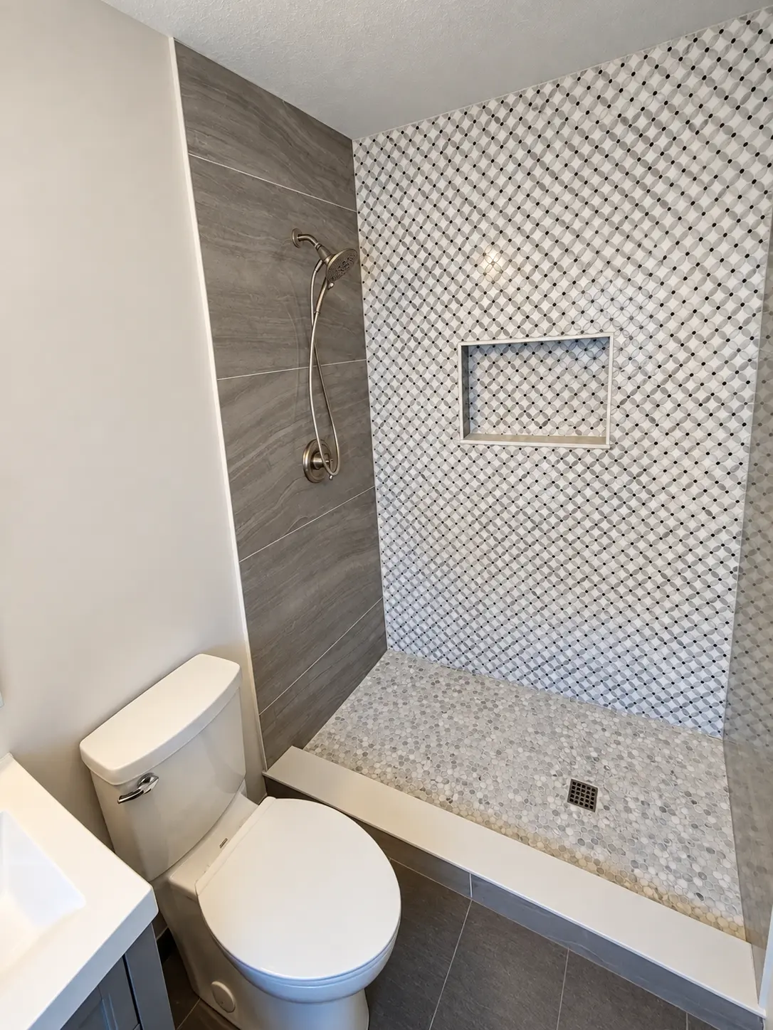Contemporary bathroom with gray wood-look tile, geometric mosaic shower wall and recessed shower niche