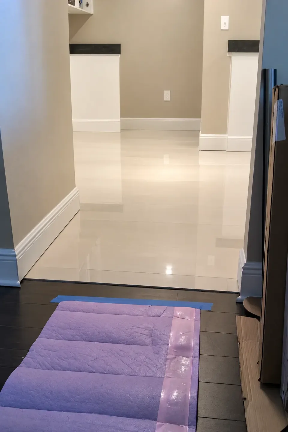 Glossy light-colored tile flooring in a residential entryway with white baseboards