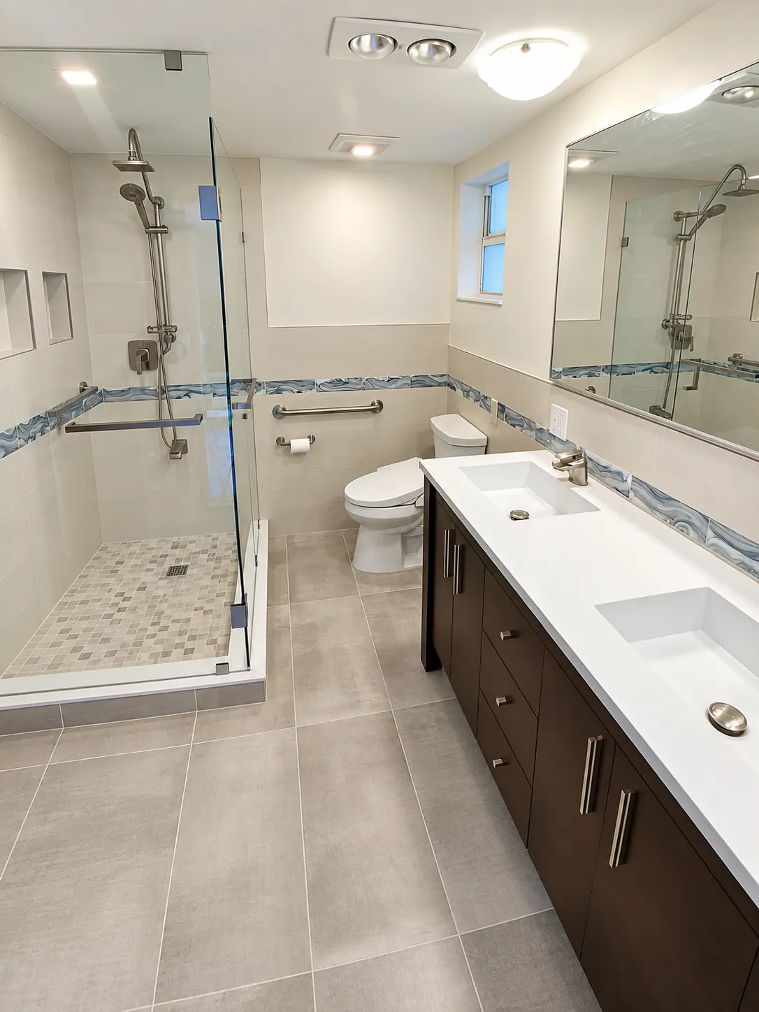 Modern bathroom remodel with dark wood double vanity, frameless glass shower and mosaic shower floor