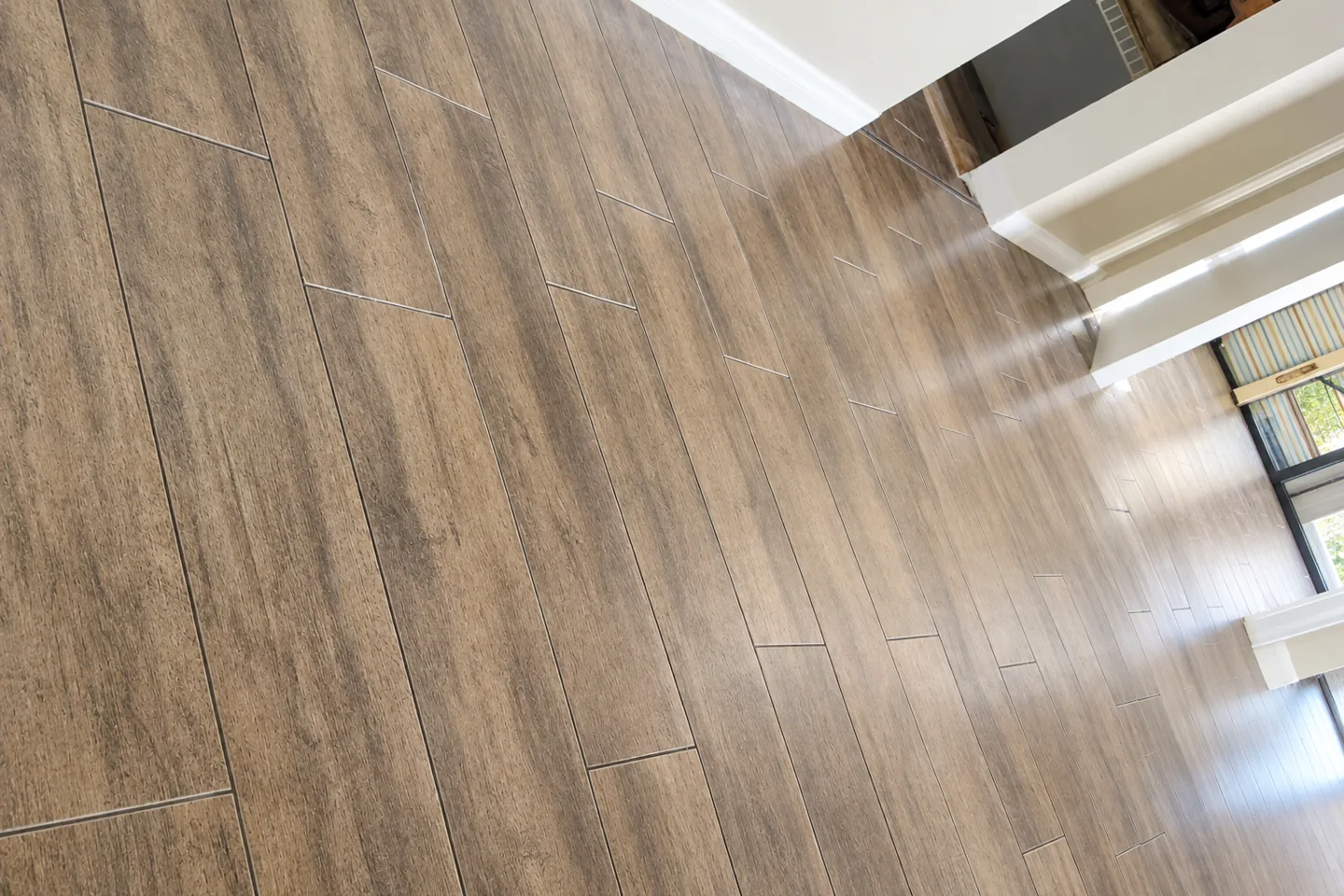 Close view of brown wood-look floor planks and their grain pattern beside a white stair railing