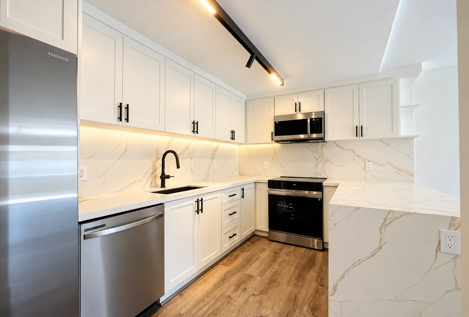 White shaker kitchen with a full-height marble-look slab backsplash, waterfall peninsula, black hardware, and under-cabinet lighting